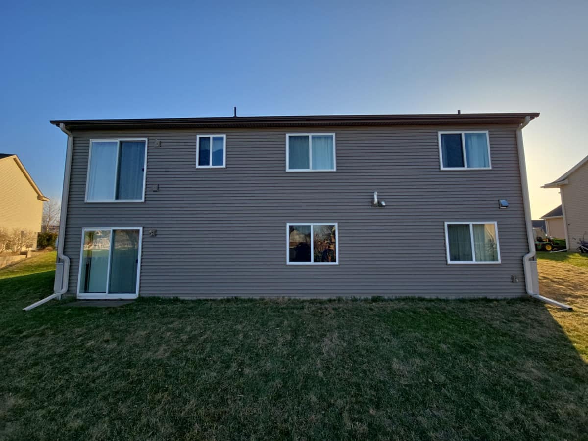 Rear of a two-story home with new vinyl siding and white gutters and downspouts in Big Lake, MN