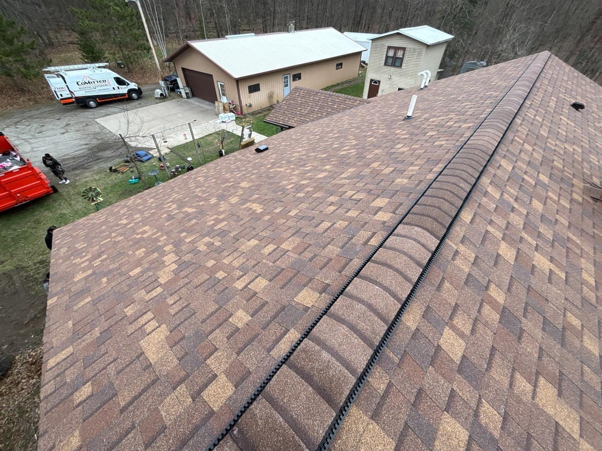 Finished brown architectural shingle roof in Brainerd, MN with a Committed 365 van in the drive