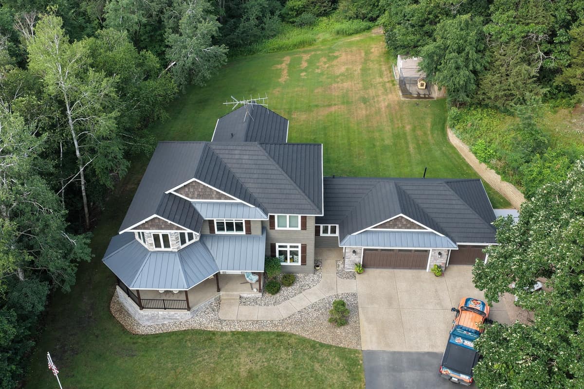 Drone view of a new dark stone-coated steel roof with metal accents on a two-story home in Clearwater, MN