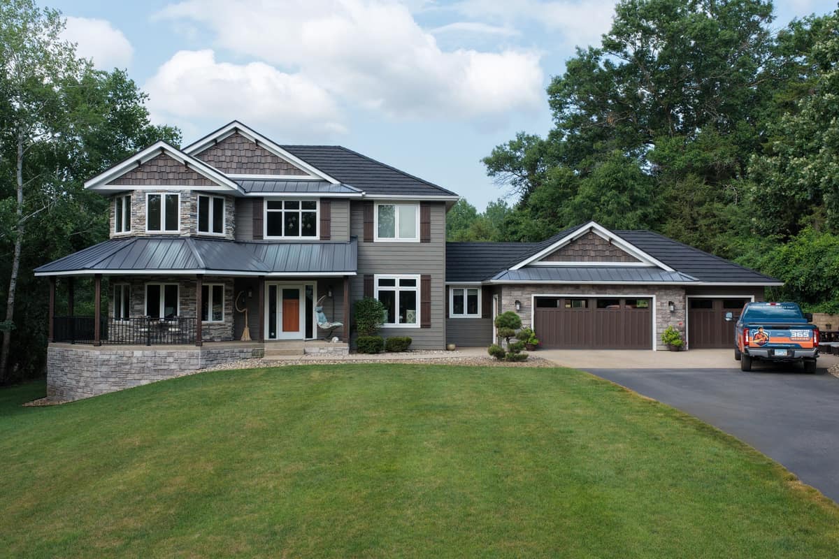 Two-story home with a new dark steel shingle roof and metal porch roof in Clearwater, MN