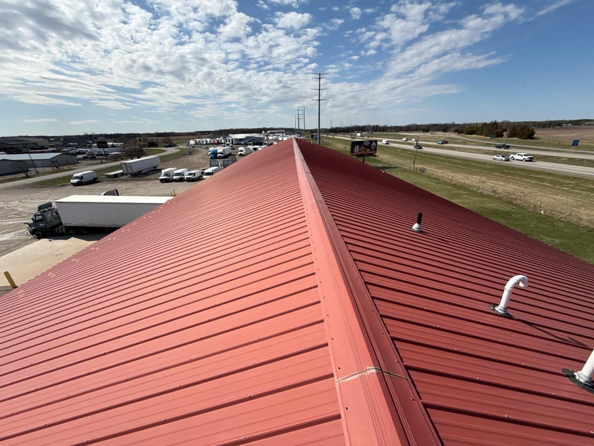 New red standing-seam metal roof on a commercial building beside Interstate 94 in Clearwater, MN