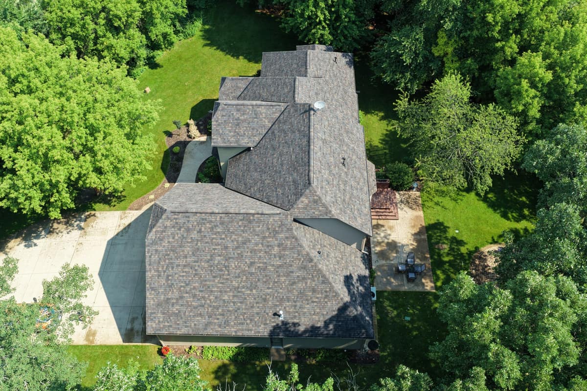 Drone view of a new shingle roof on a wooded lot in Cold Spring, MN
