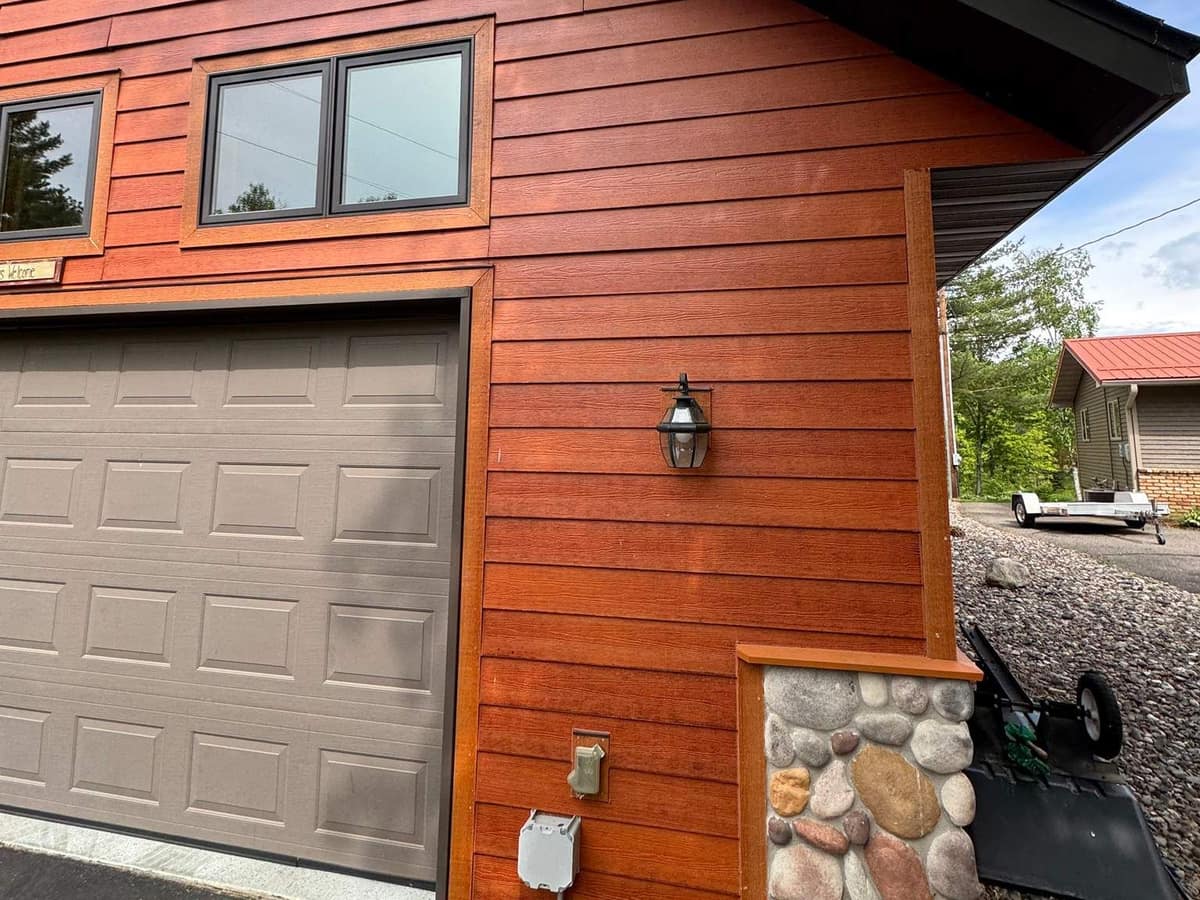 New cedar-tone lap siding with stone accent beside a garage in Crosslake, MN