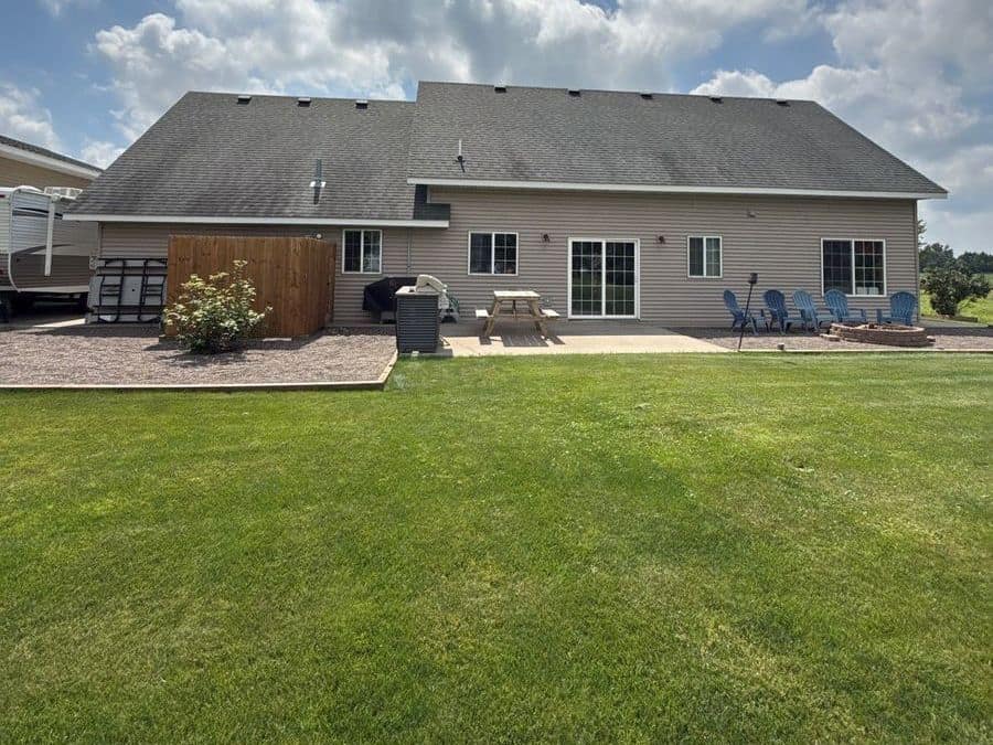 Back of a tan-sided home with a newly shingled gray roof in Foley, MN