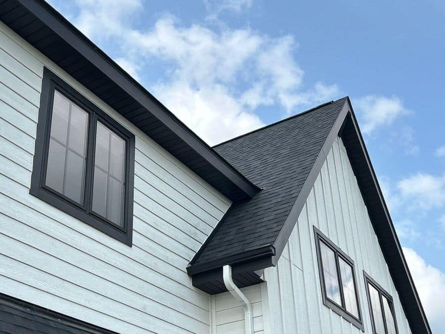 White siding, black-trimmed windows, a white downspout and new shingles on a home in Foley, MN