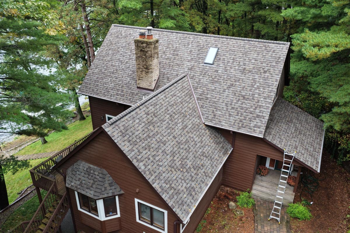 Drone view of a new shingle roof on a wooded lake home in Nisswa, MN