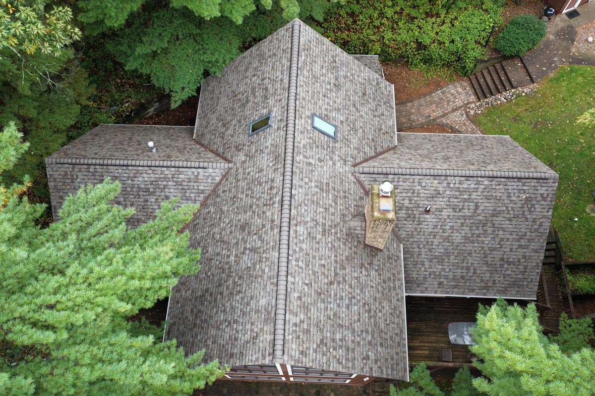 Top-down drone view of a new shingle roof with skylights on a wooded lot in Nisswa, MN
