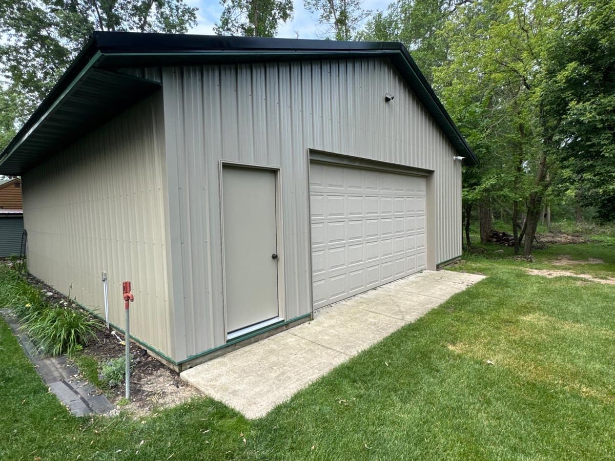 Tan steel-sided detached garage with green trim in Paynesville, MN