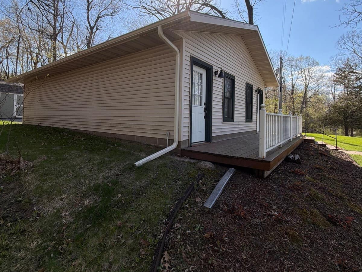 Tan vinyl-sided home with a white gutter and downspout in Paynesville, MN