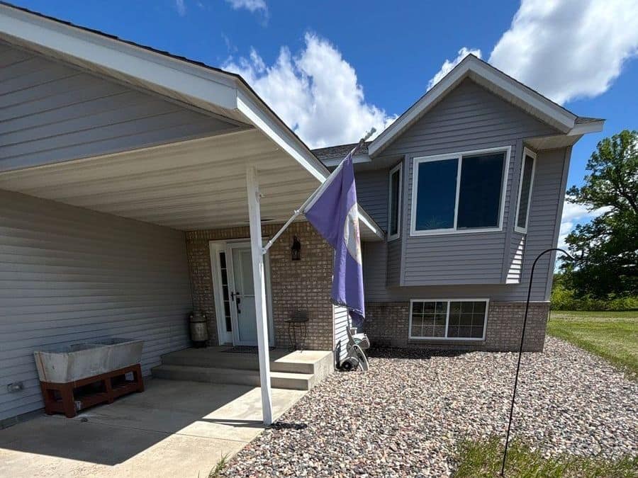 Gray vinyl-sided home with a brick base and a covered entry in Rice, MN
