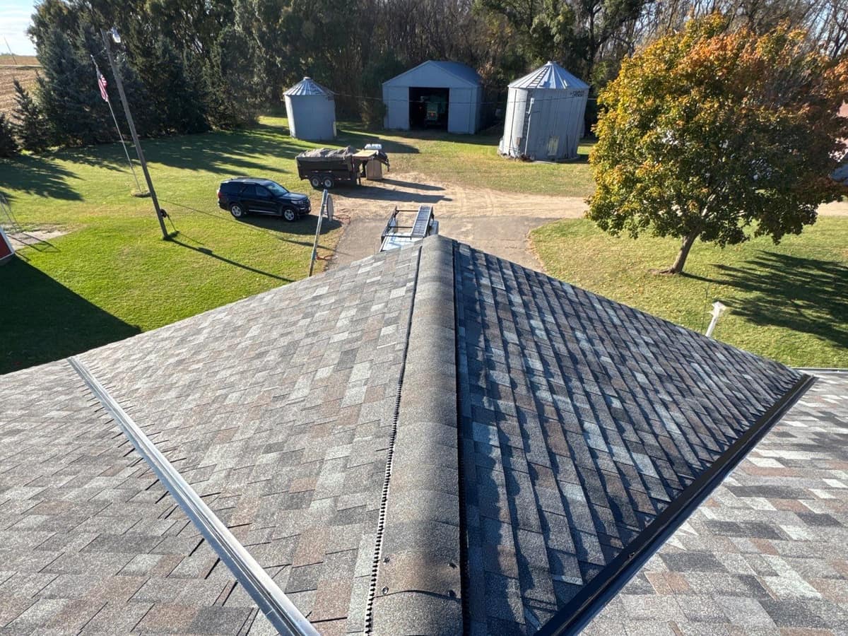 Architectural shingle roof ridge on a farm home with grain bins beyond in Richmond, MN