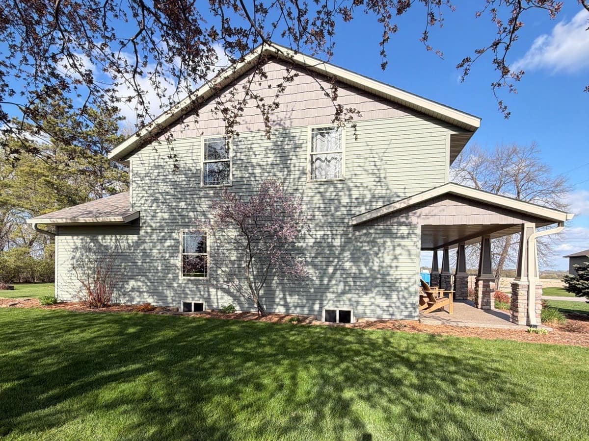 Sage green lap siding and a covered porch on a two-story home in Richmond, MN