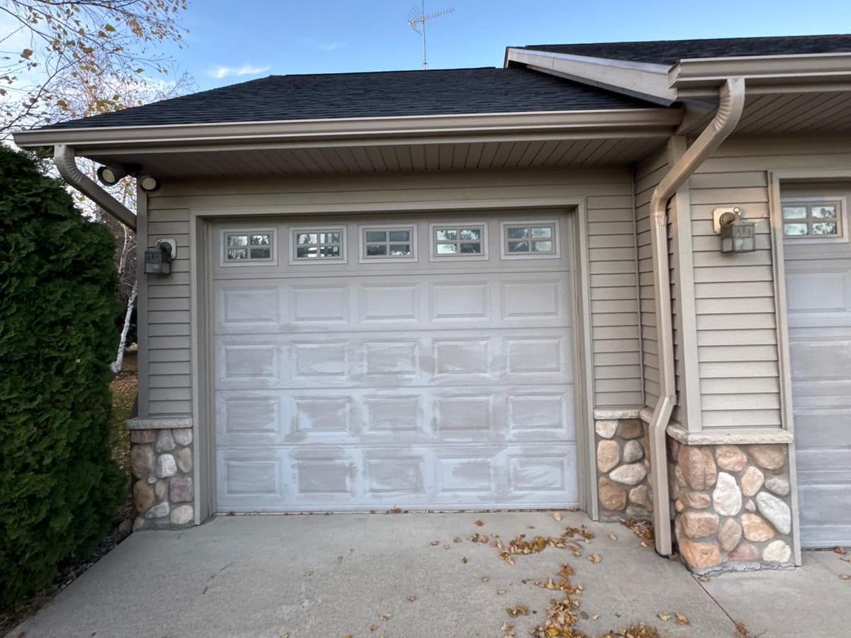 Tan siding, seamless gutters and downspouts on a garage with stone accents in Richmond, MN