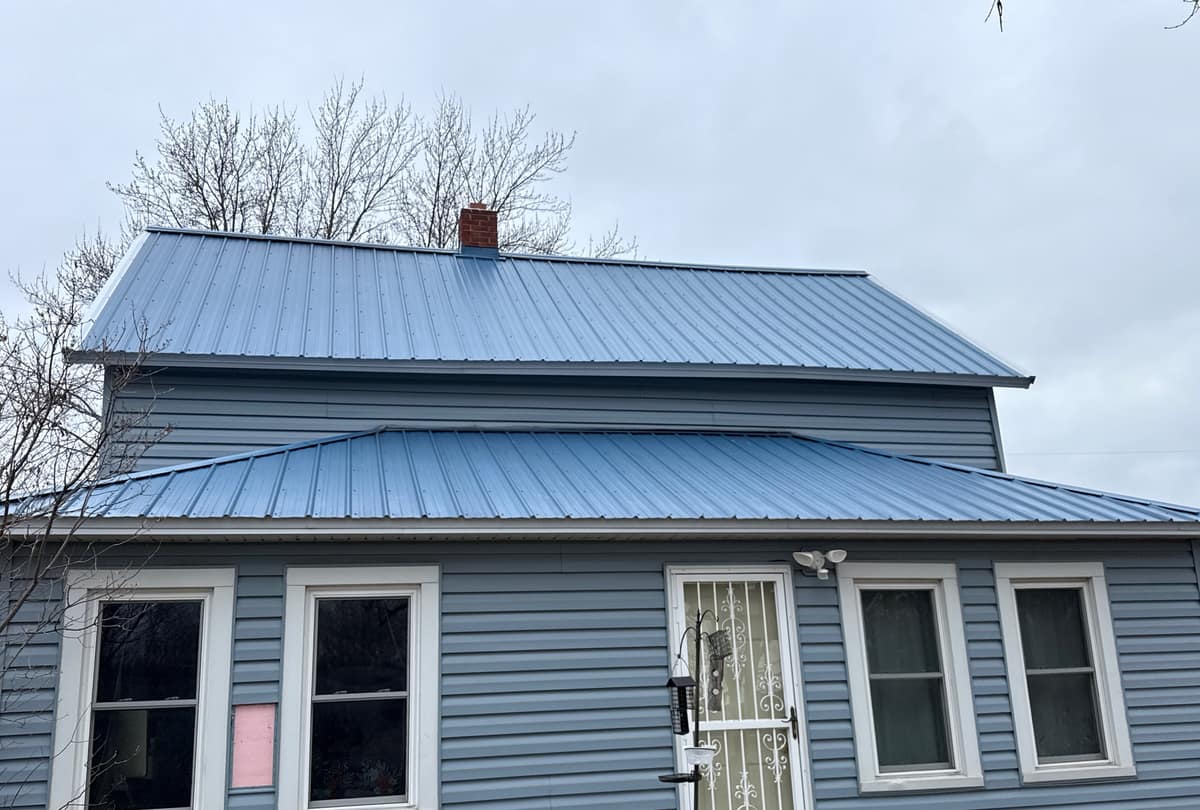 New blue standing-seam metal roof over blue siding on a two-story home in St. Joseph, MN