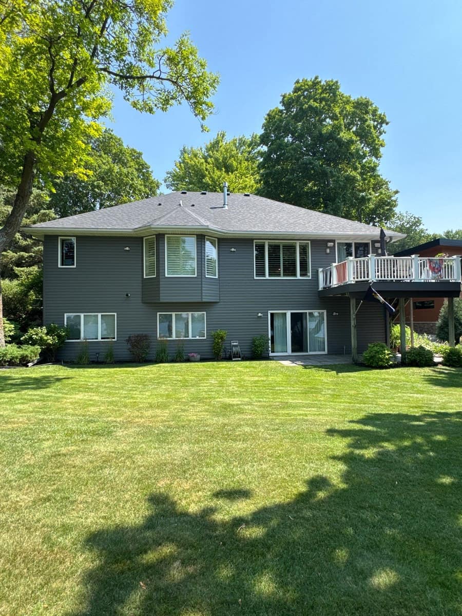 Back of a two-story Alexandria home with gray siding, a deck and a new dark shingle roof