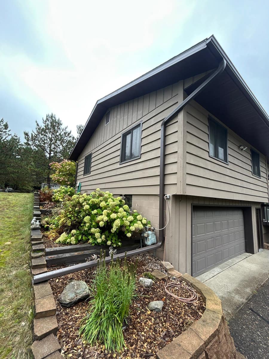 Baxter home with new dark brown fascia, gutters and downspouts above tan lap siding
