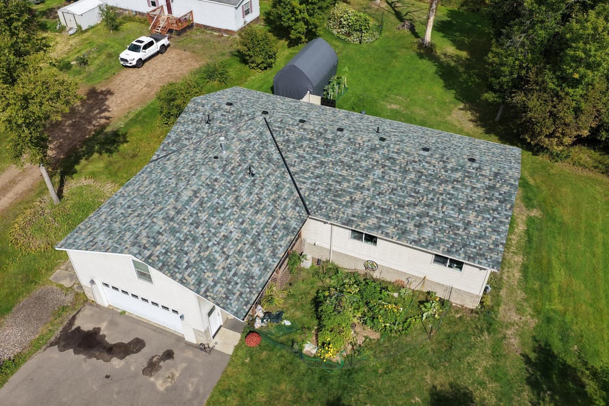 Drone view of a finished blue-green blend shingle roof on an L-shaped ranch home in Brainerd, MN