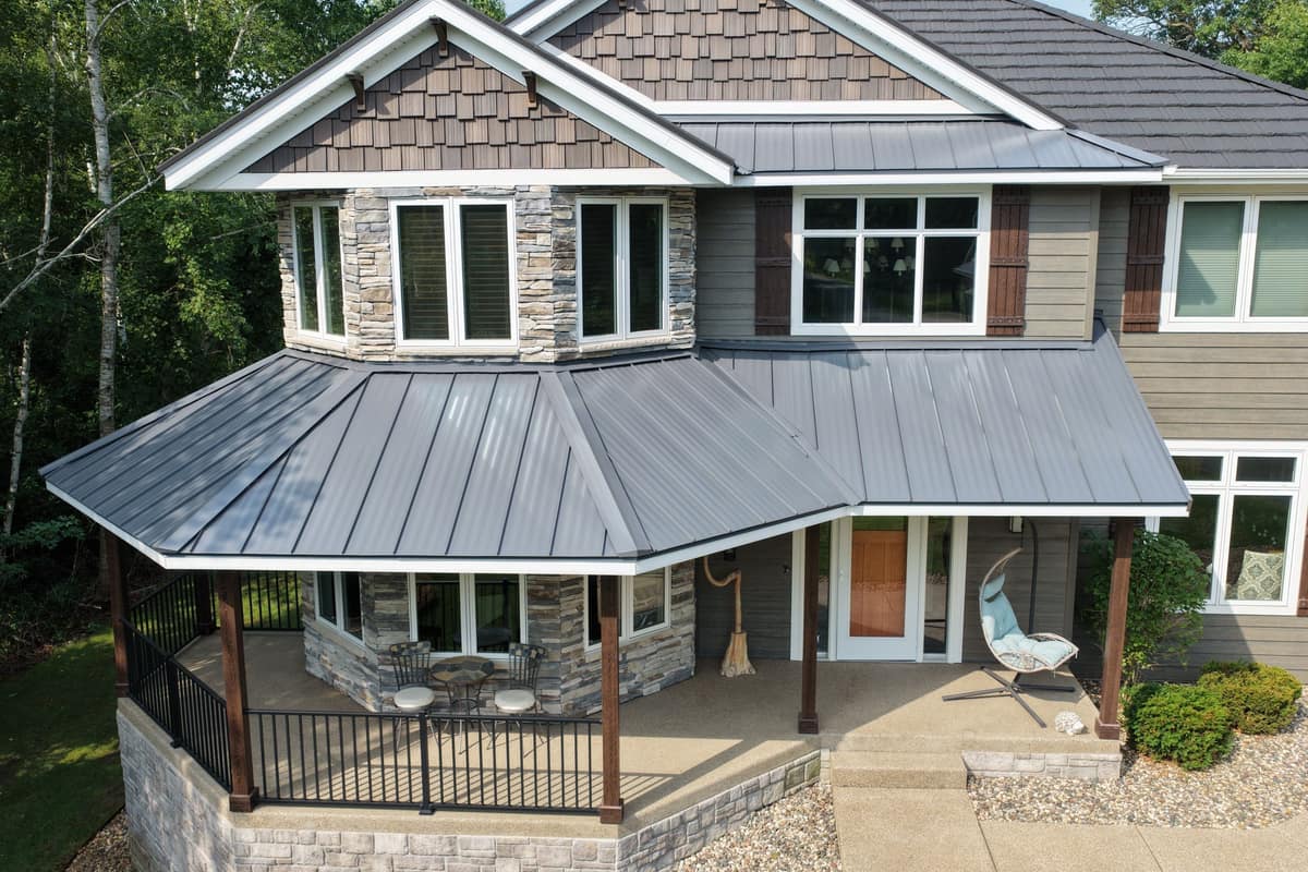 Drone view of a Clearwater, MN home with a new charcoal steel roof and gray standing seam porch roof