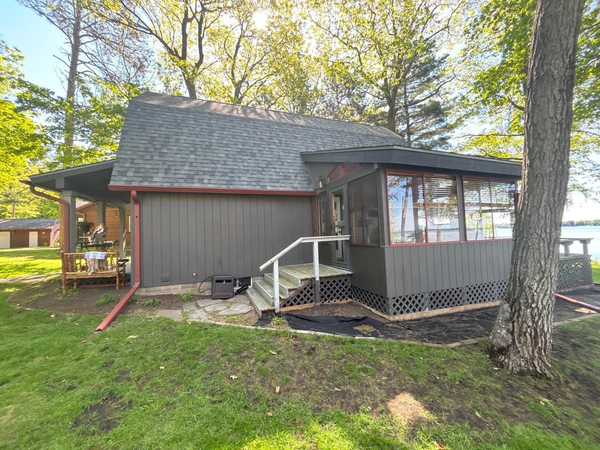 Side of the Crosslake cottage with a screened porch wing under the new shingles