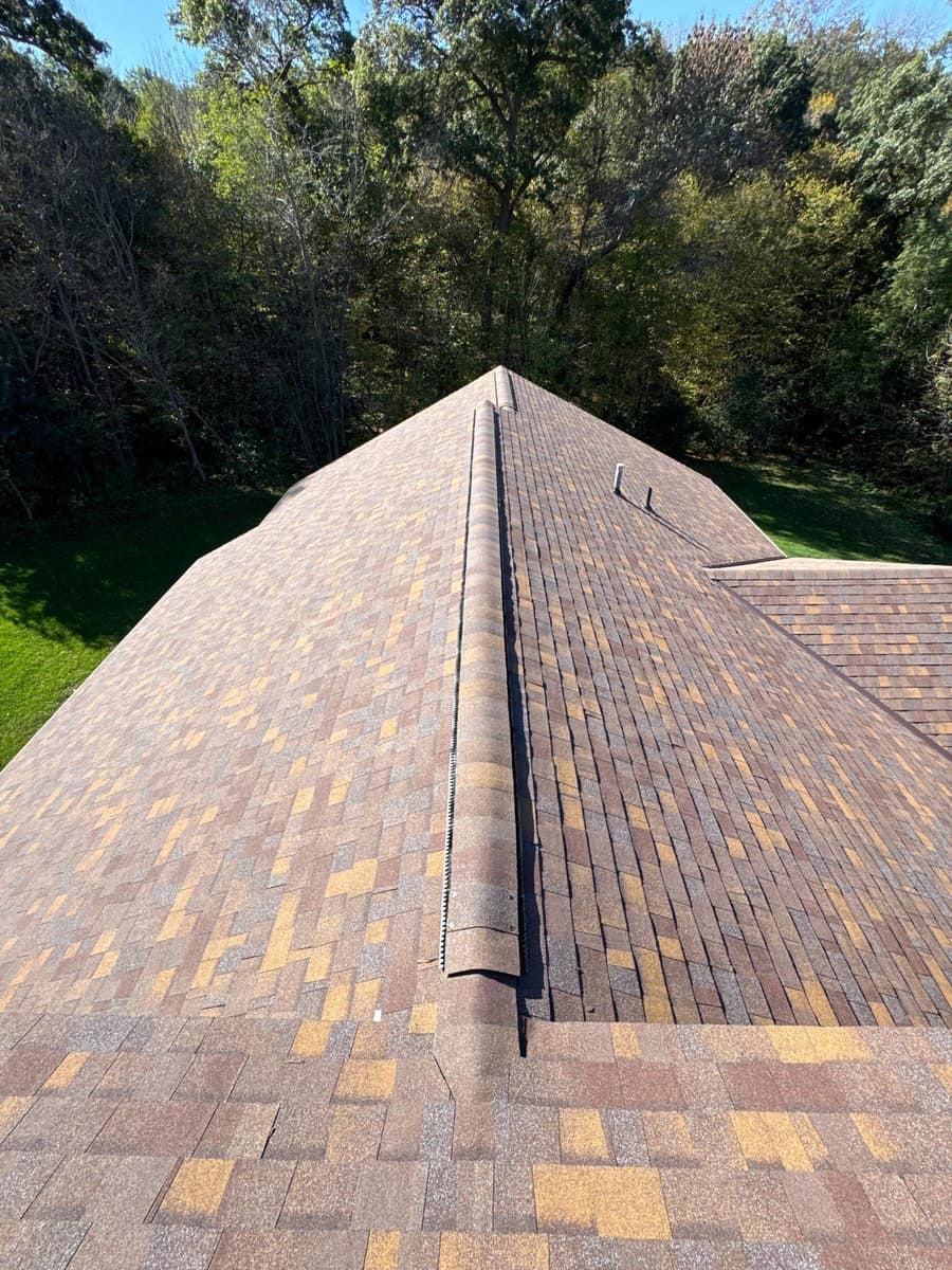 Ridge vent running under the cap shingles on the new brown blend roof in Kimball