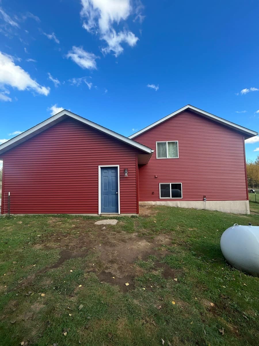 Side of a Milaca, MN home with new barn red vinyl siding and a blue service door
