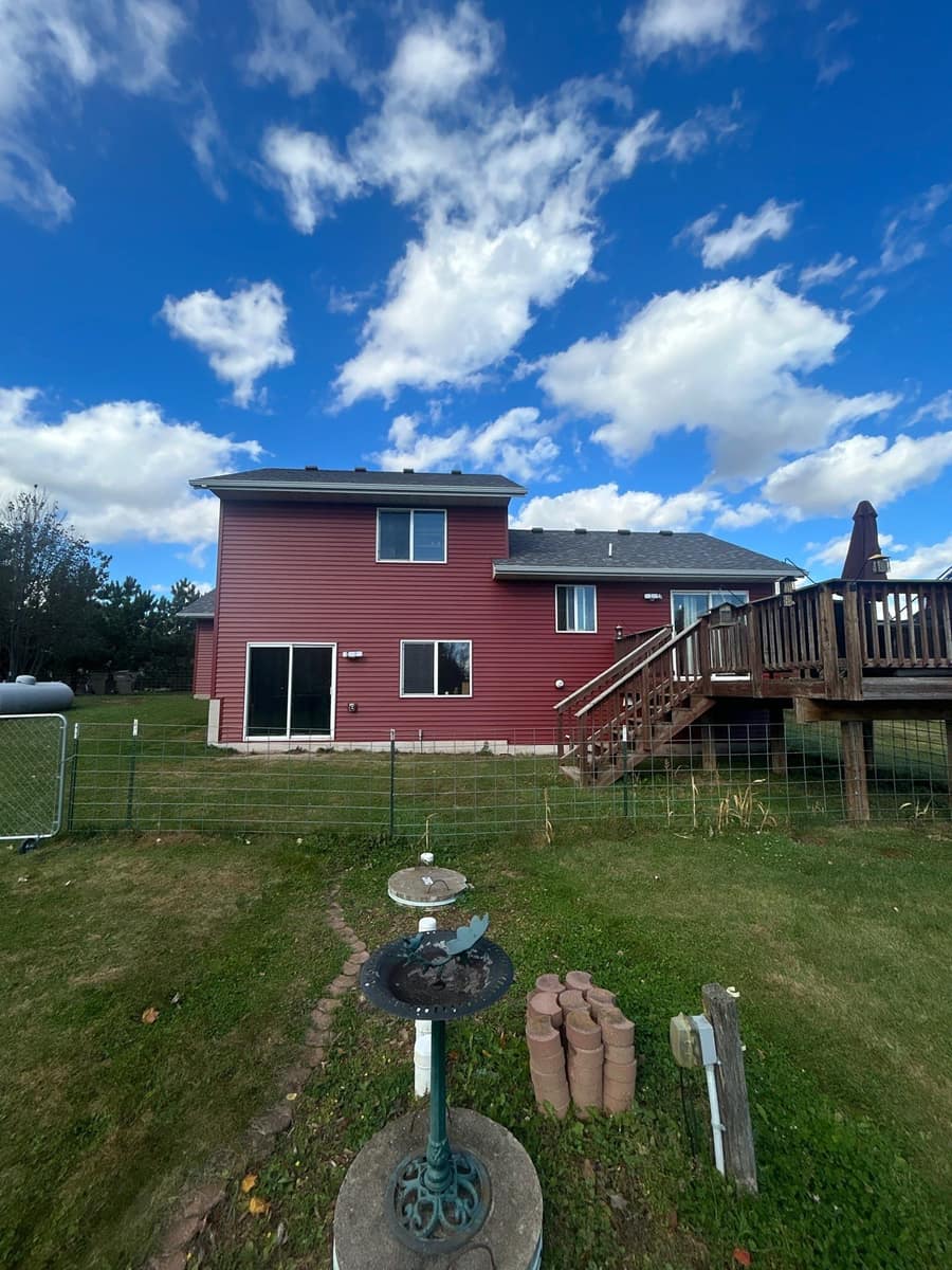 Back of the Milaca split-level with new red siding, a new roof and a raised wood deck