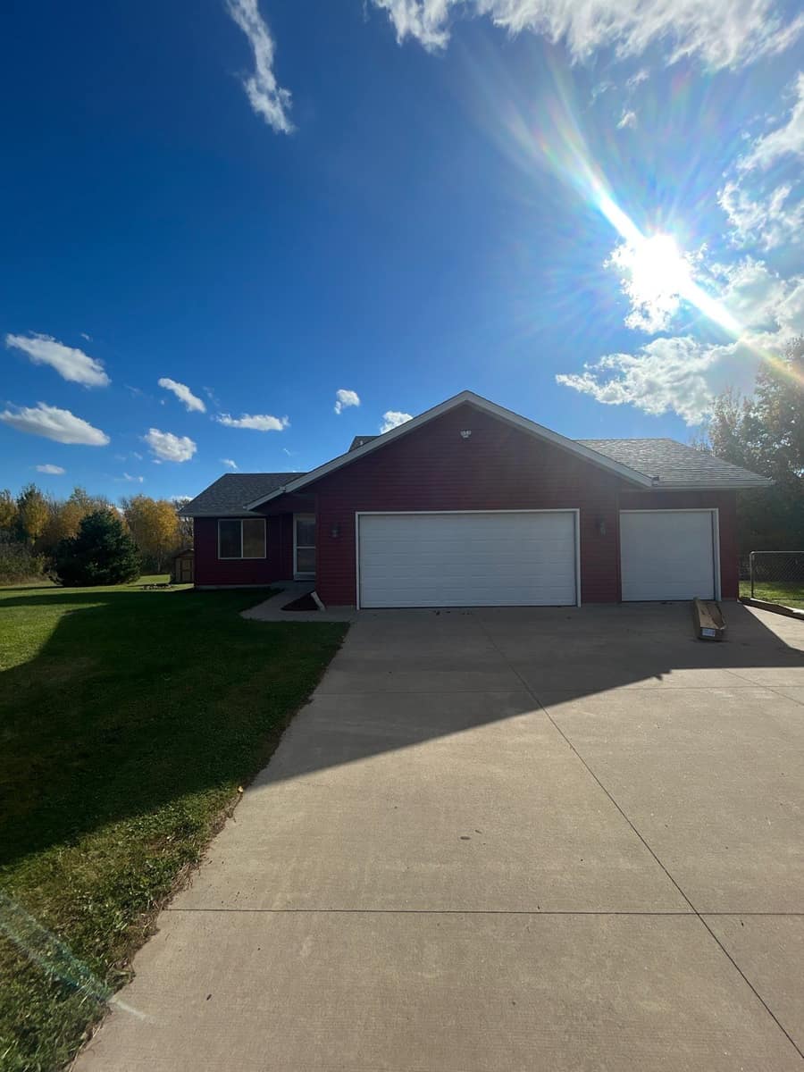 Front of the Milaca home with a three-stall garage, new red siding and a new shingle roof