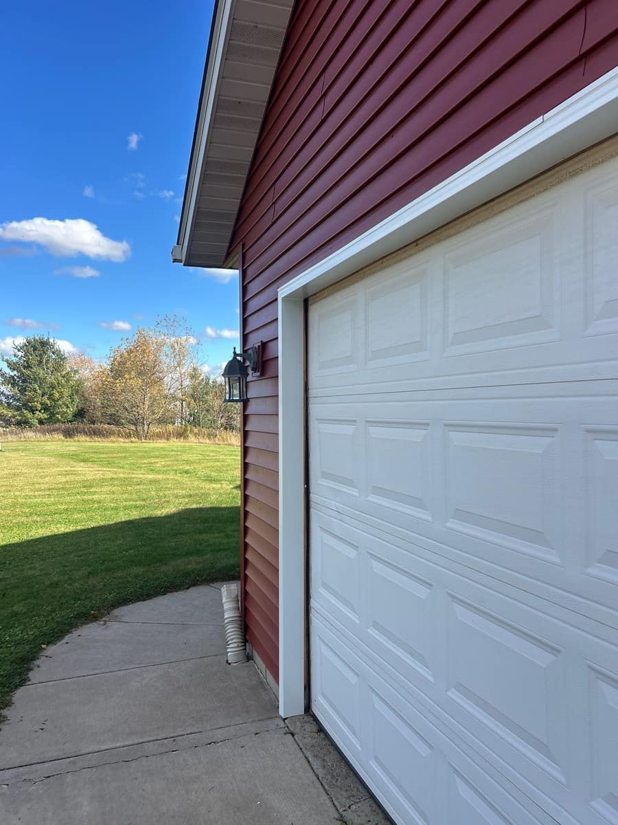 White trim around a garage door set in new barn red siding in Milaca