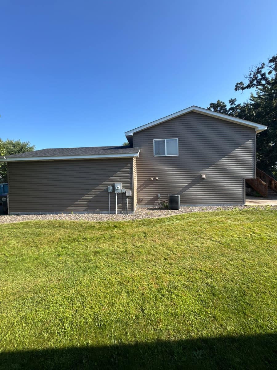 Side of a split-level Monticello home with new taupe vinyl siding and a new roof
