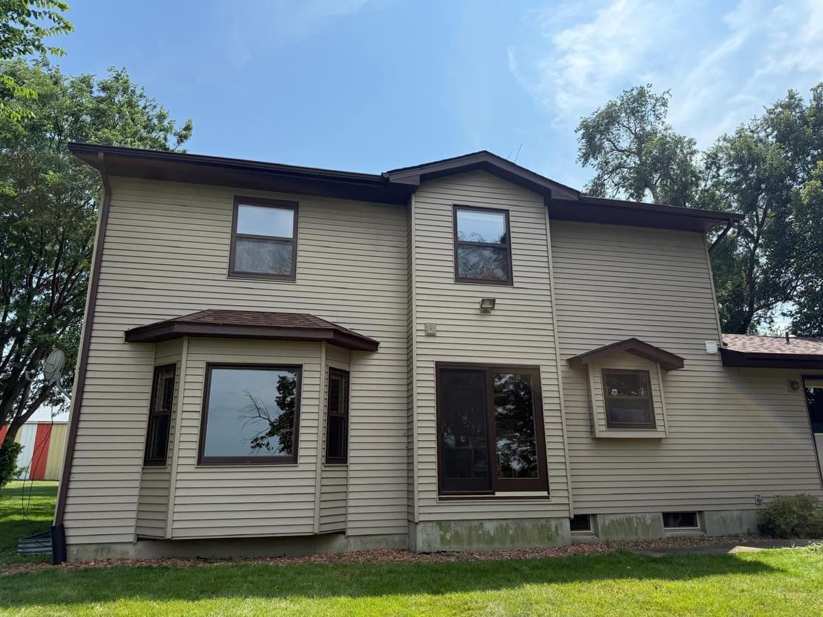 Back of the Monticello home with tan siding, bay windows and the new roof edge