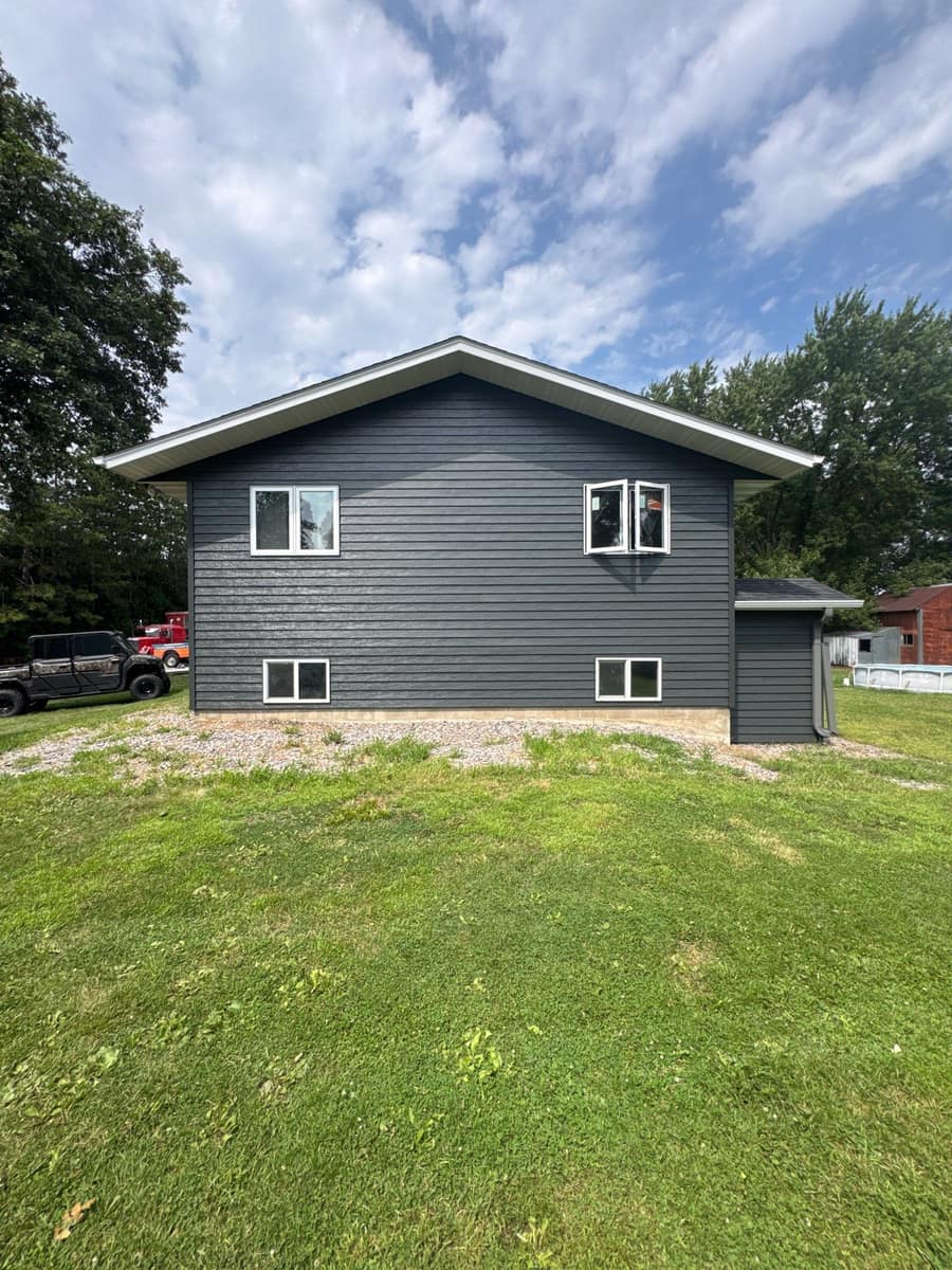 Split-level home in Paynesville, MN with new slate gray steel siding, white trim and a charcoal roof