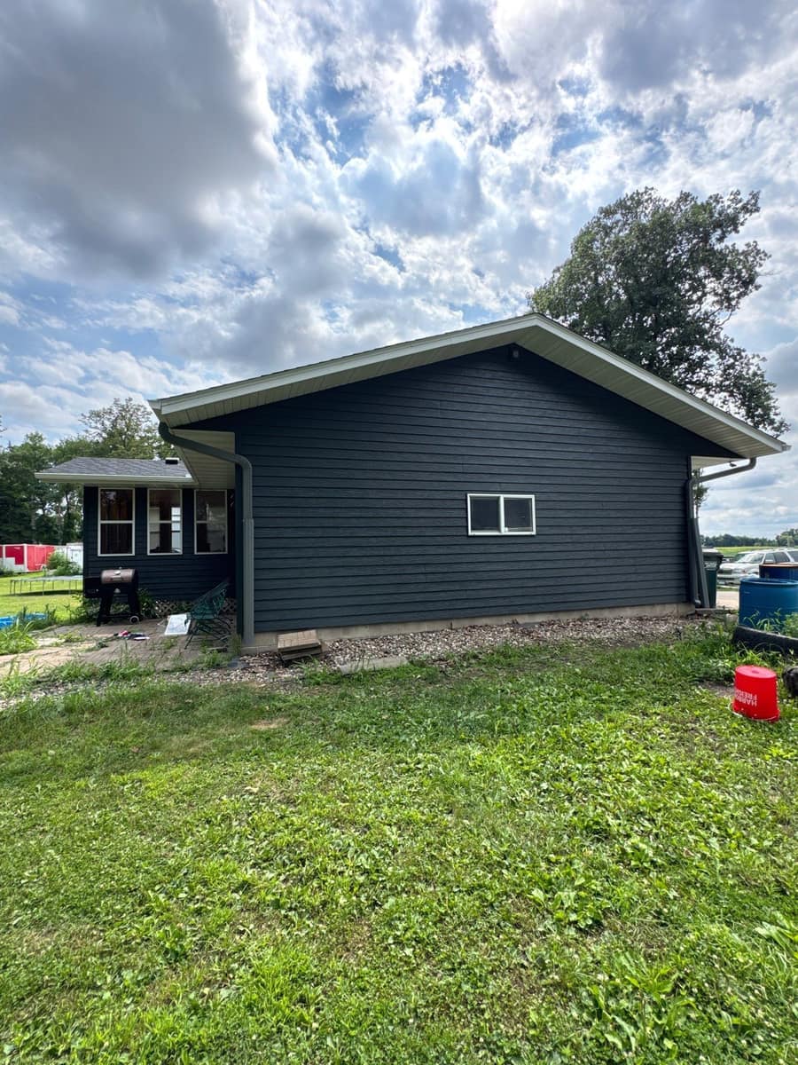 Side of the Paynesville home and its lower wing with new dark gray siding and gutters