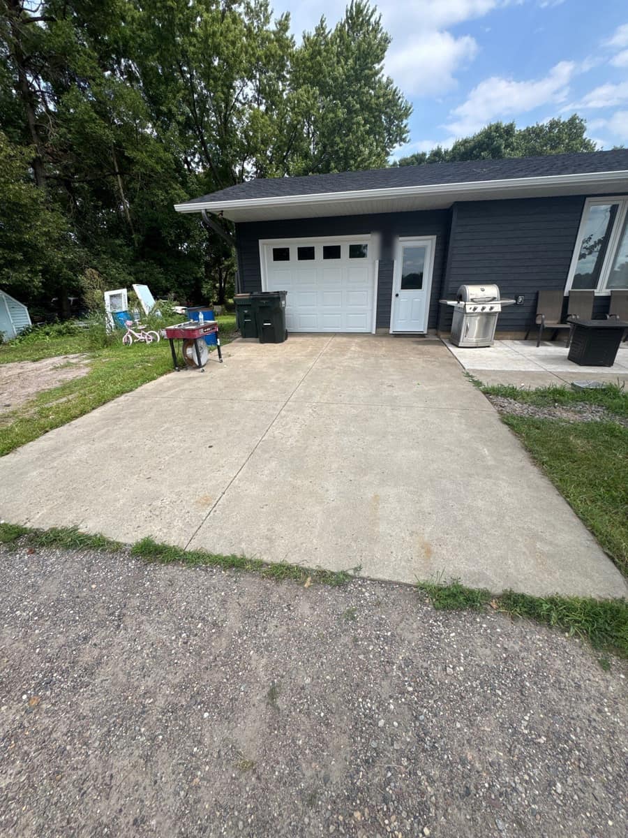 Attached garage end of the Paynesville home with new gray siding and a white overhead door