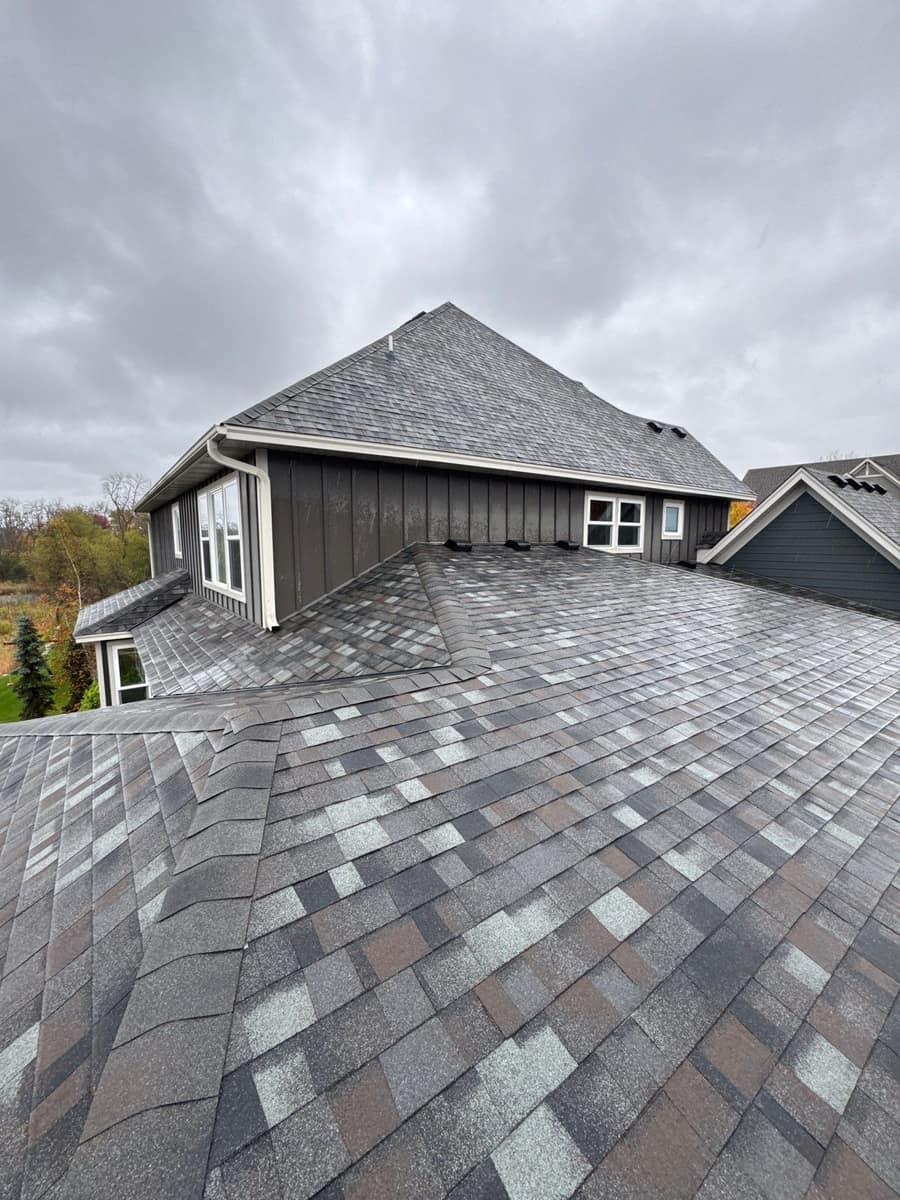 New multi-tone gray shingle roof on a large two-story Plymouth, MN home with board and batten siding