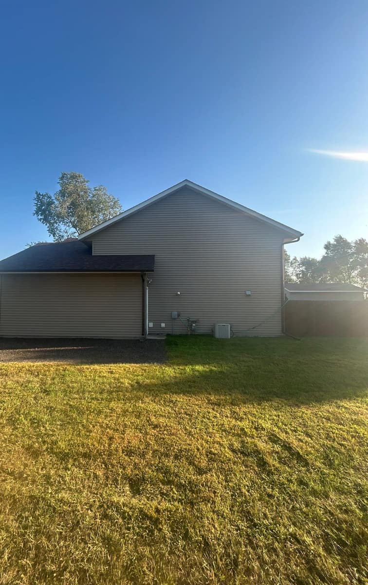 Split-level home in Rice, MN with beige siding and a new brown shingle roof in morning light