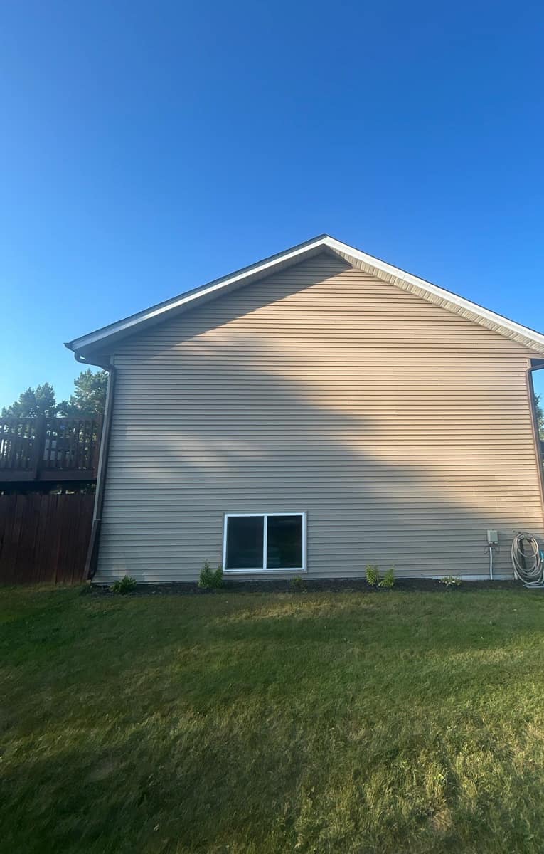 Gable end of the Rice home with beige siding under the new roof edge