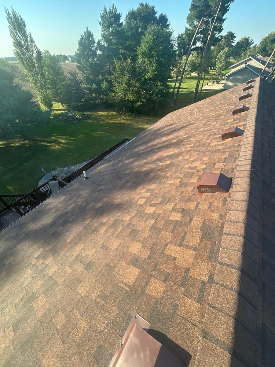 Row of brown box vents along the ridge of the new shingle roof in Rice