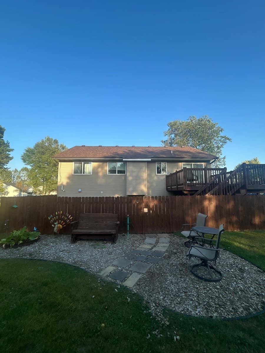 Fenced back yard and patio with the new roof on the house beyond, in Rice