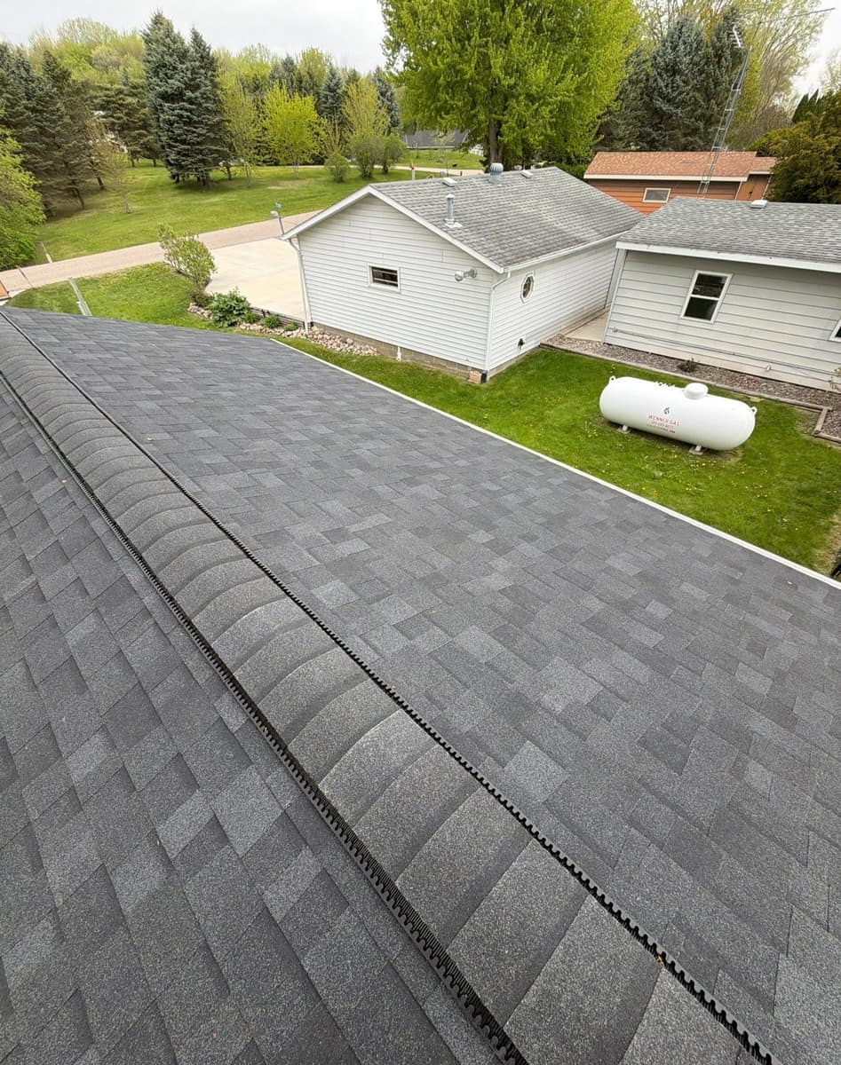 Ridge vent under cap shingles running along the new dark gray roof in Richmond