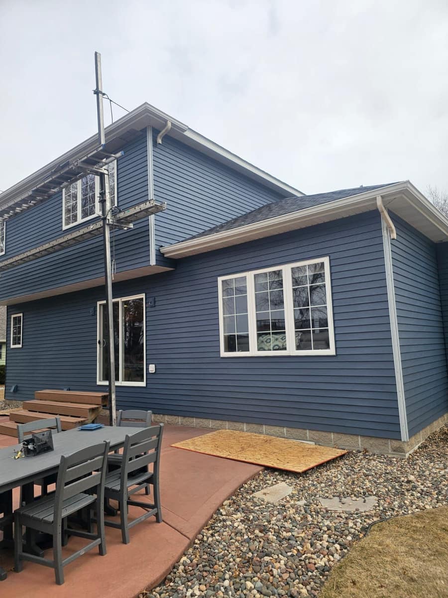 Back patio side of the Sartell home with new blue siding and gutters