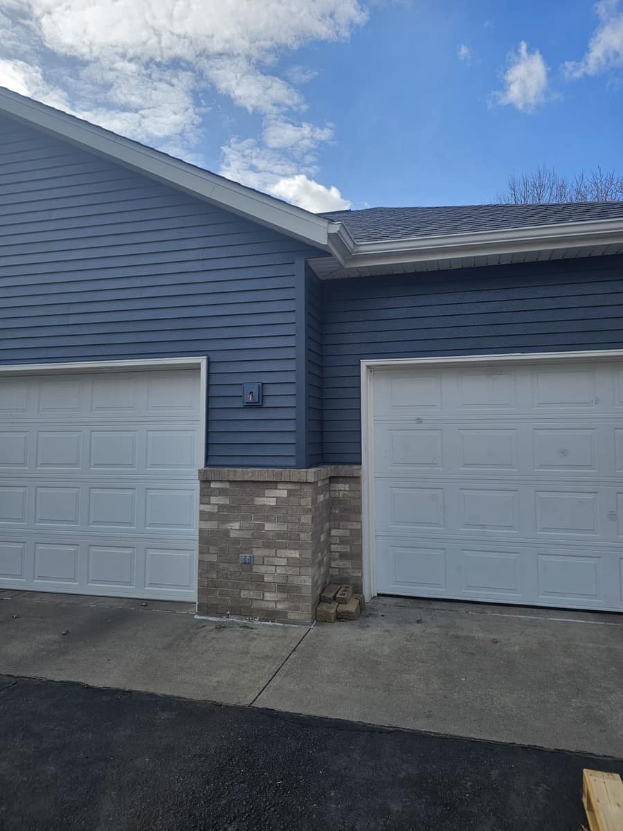 Garage wing of the Sartell home with new blue siding and roof