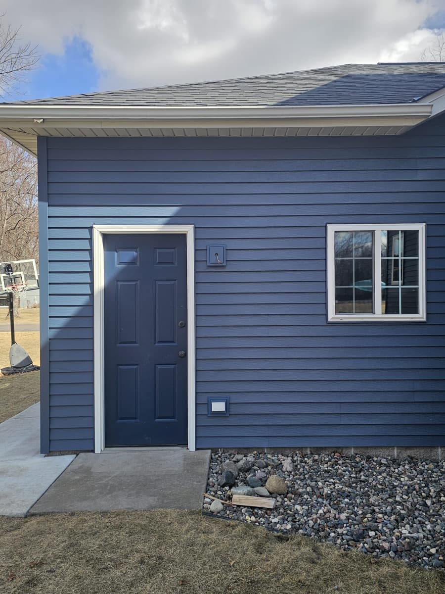 Side entry door framed by new blue siding on the Sartell home