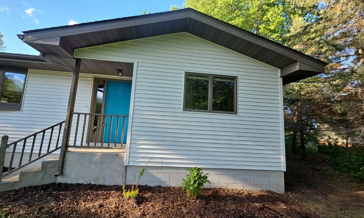 Entry side of the Sartell home with new white siding and dark fascia