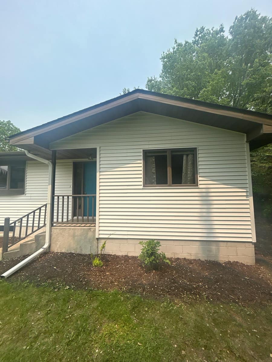 Corner of the Sartell home with new white siding and gutters