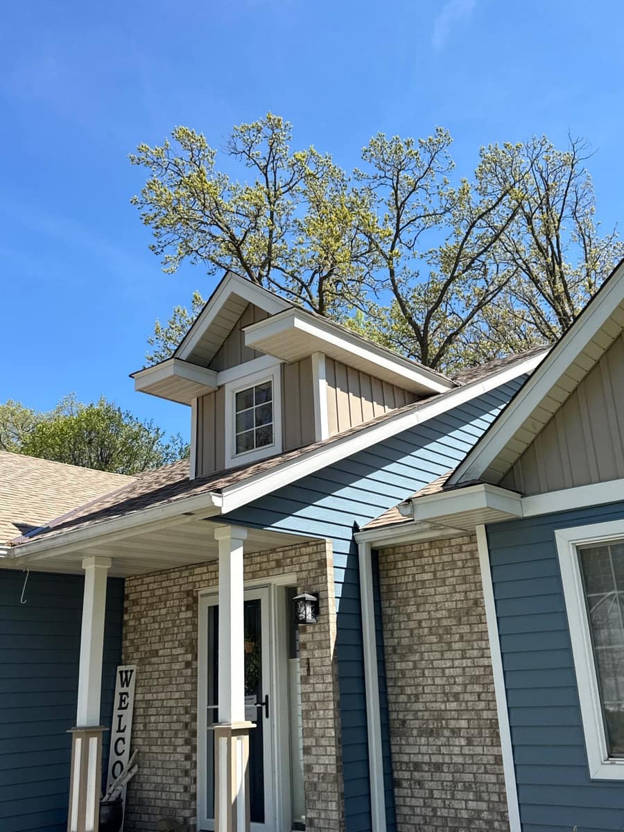 Front entry of the Sartell home with new blue lap siding, tan board and batten gables and brick