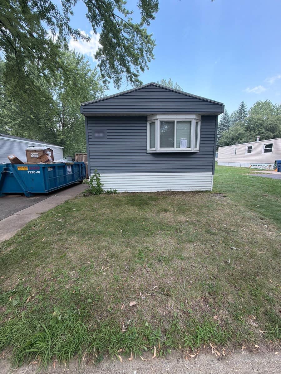 Manufactured home in Sartell, MN with new gray vinyl siding and white skirting