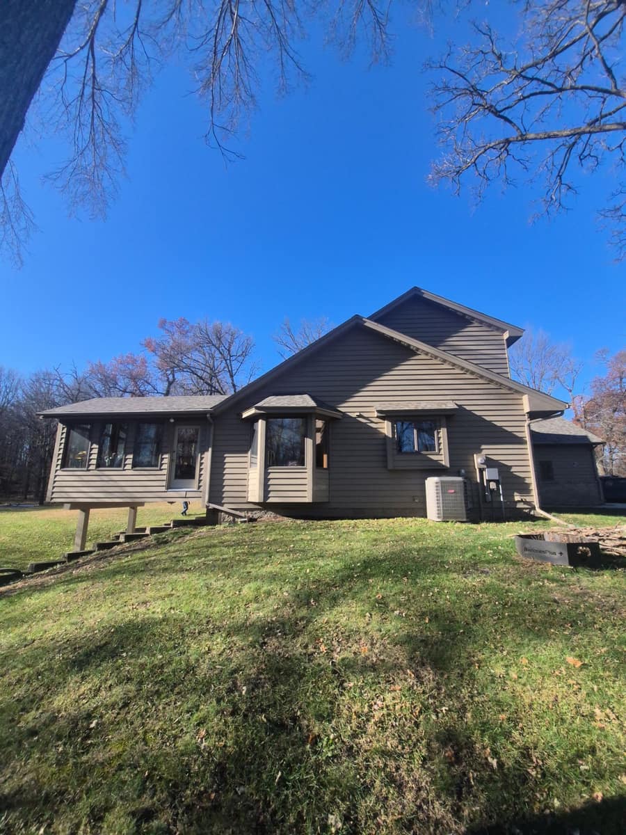 Two-story St. Augusta home with taupe siding and a new tan blend shingle roof under bare oak trees