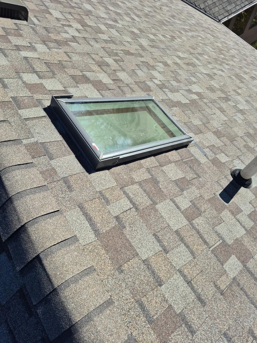 Skylight and a plumbing vent worked into the new tan shingles on the St. Augusta roof