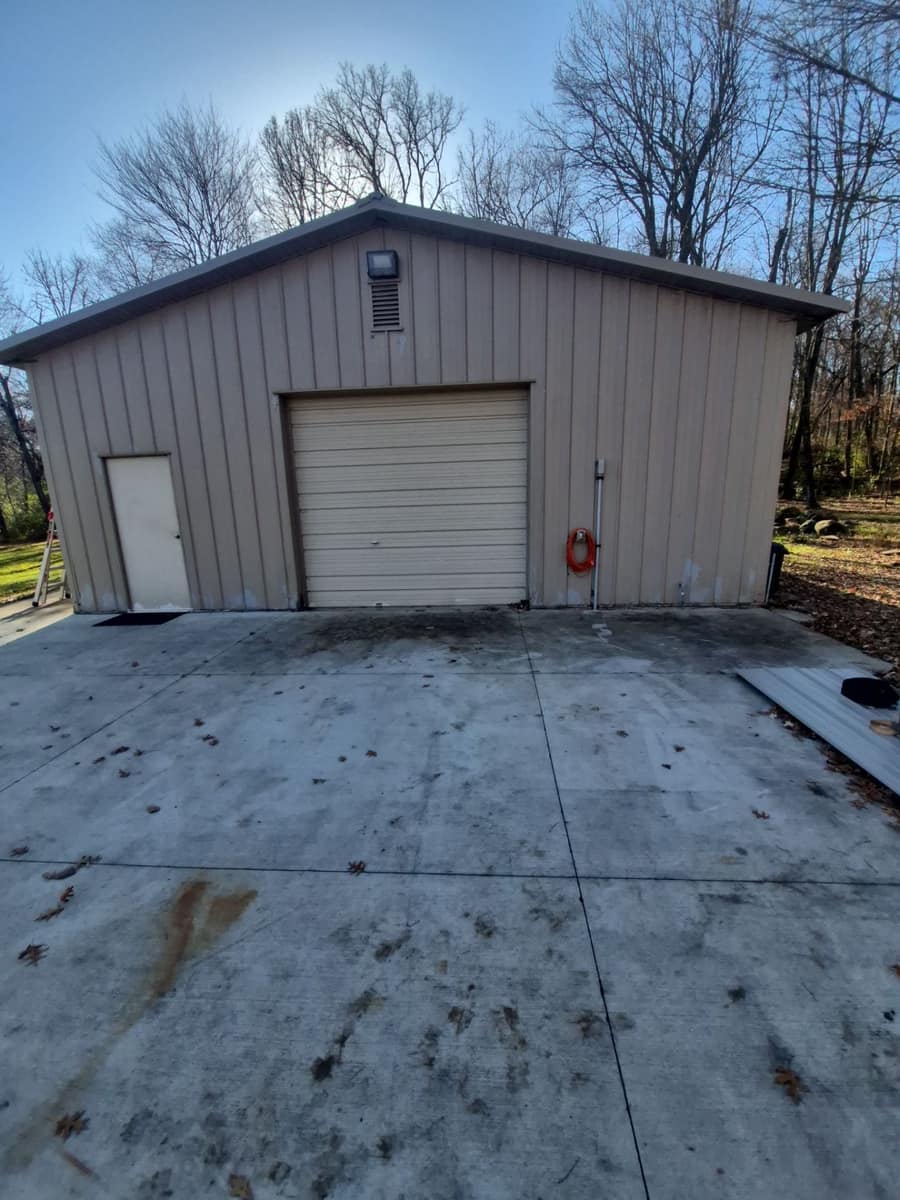Tan steel garage with an overhead door and a service door at the end of a concrete apron in St. Augusta
