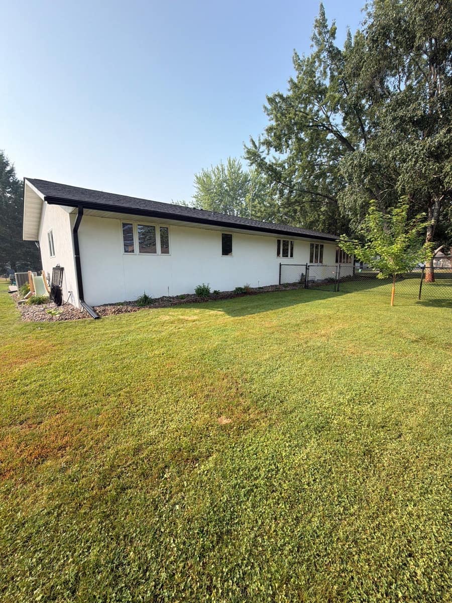 Long white ranch home in St. Cloud with a new dark roof edge and gutters